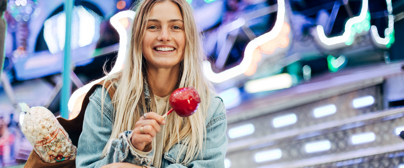 Junge Frau mit Popcorntüte und Paradiesapfel für Karussell