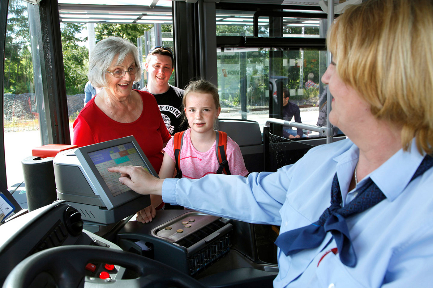 Eine Busfahrerin lässt Fahrgäste einsteigen.