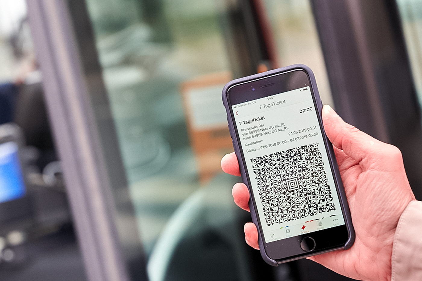 Eine Hand hält in Smartphone mit einem QR-Code zum E-Ticket.