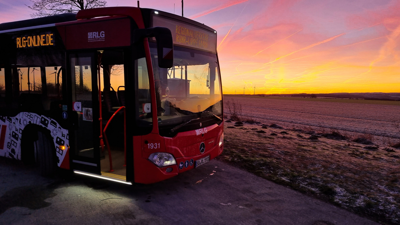Frontpartie eines RegioBusses in der Dämmerung. Im Hintergrund einige Windräder